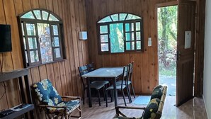 A wooden-paneled room with a dining table, chairs, a sofa, and a ceiling fan.