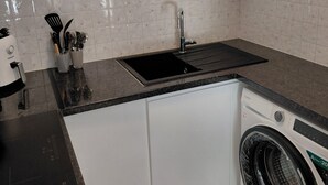 A kitchen with a sink, countertop, cabinets, and a front-loading washing machine. - 2-room apartment with a terrace (Cannes)
