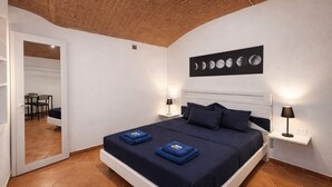 A bedroom with a bed, bedside lamps, a wall-mounted moon phases artwork, and a door leading to a bathroom. - Elegant 5-day loft, Milan Dateo, tricolor (Milano)