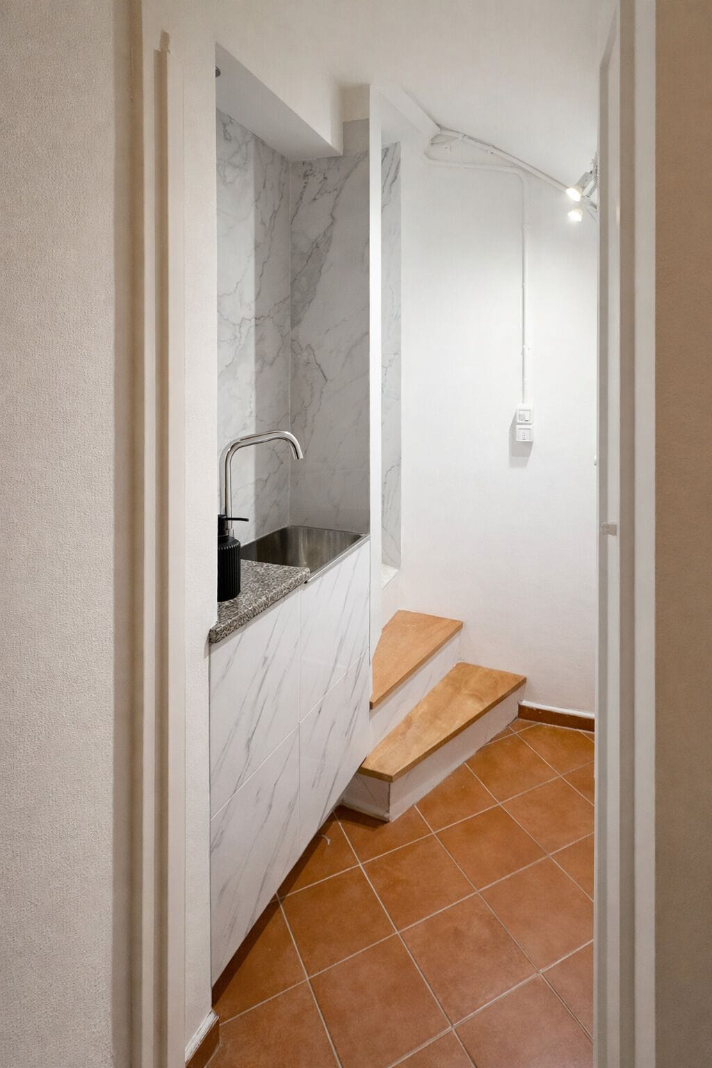 A bathroom with a marble wall, a sink, and a shower area.