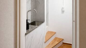 A bathroom with a marble wall, a sink, and a shower area.