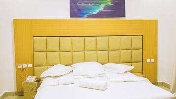 Un lit avec une tête de lit, des oreillers blancs et une couverture pliée.