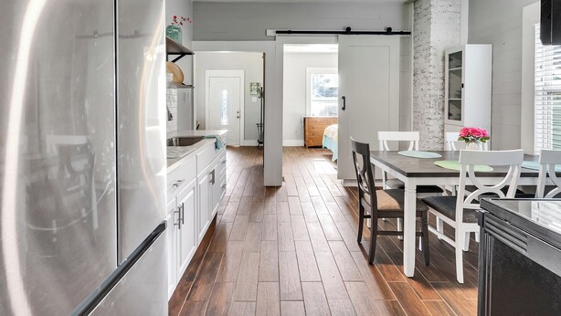 Una cucina moderna con frigorifero, zona pranzo con tavolo e sedie e ventilatore a soffitto.