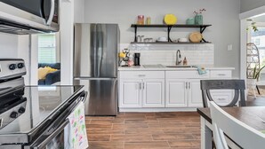 Una cucina moderna con elettrodomestici in acciaio inossidabile, mobili bianchi e un pavimento a disegno a spina di pesce.