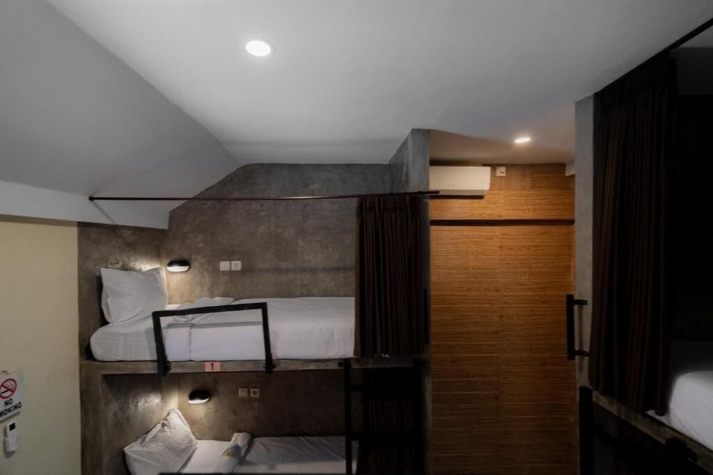 Une chambre avec un lit superposé, un mur en bois, un panneau «interdiction de fumer» et une petite fenêtre.
