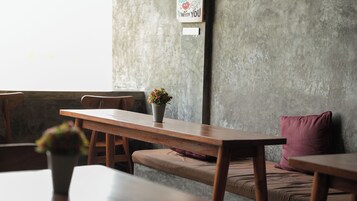 A minimalist cafe interior with a wooden table, a bench, and a potted plant.