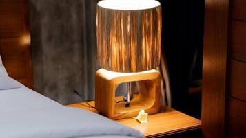 A bed with a wooden nightstand, a lamp, and a curtain.