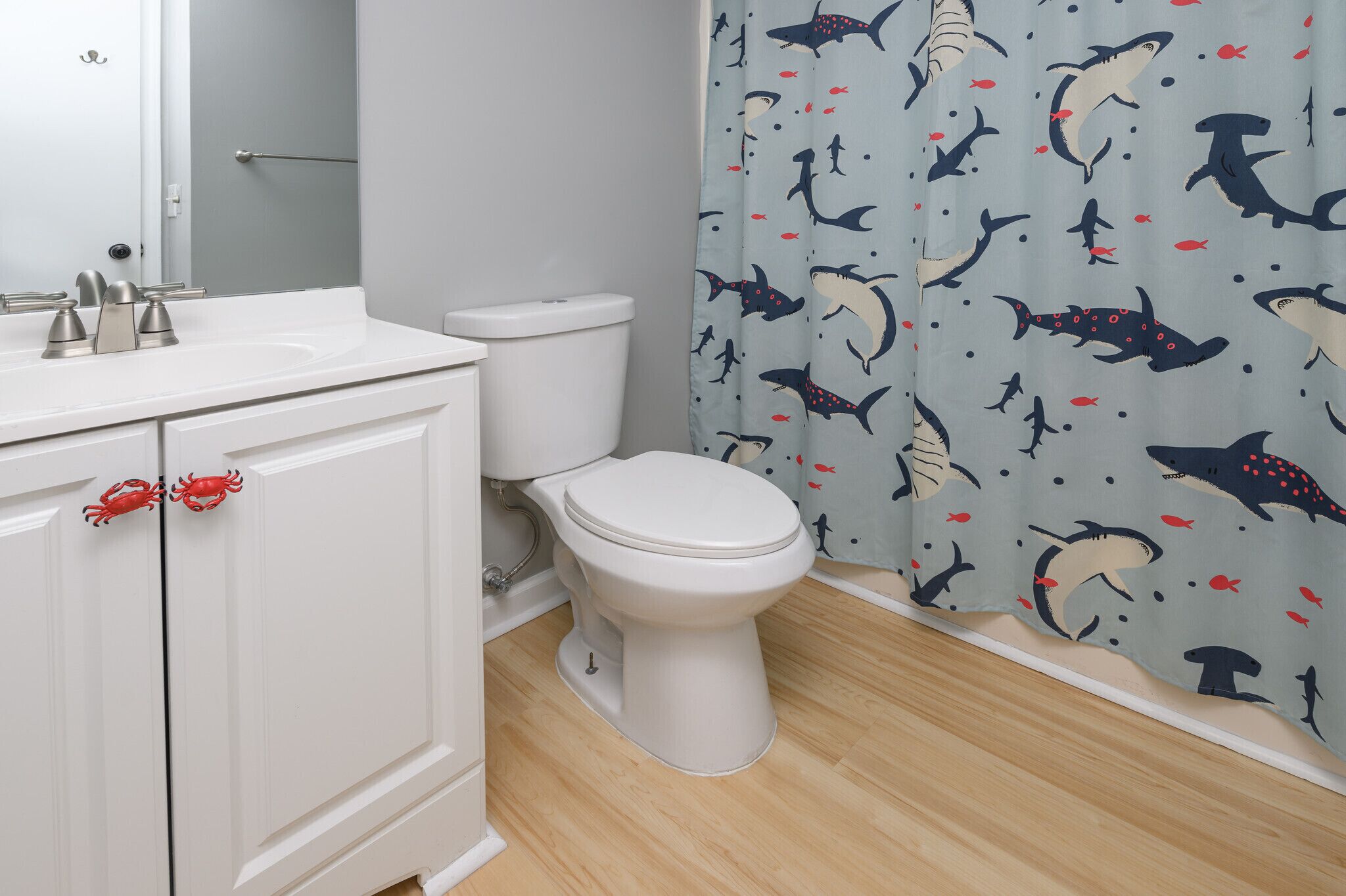 Ein Badezimmer mit Toilette, Waschbecken und einer Duschvorhang mit Hai-Muster.