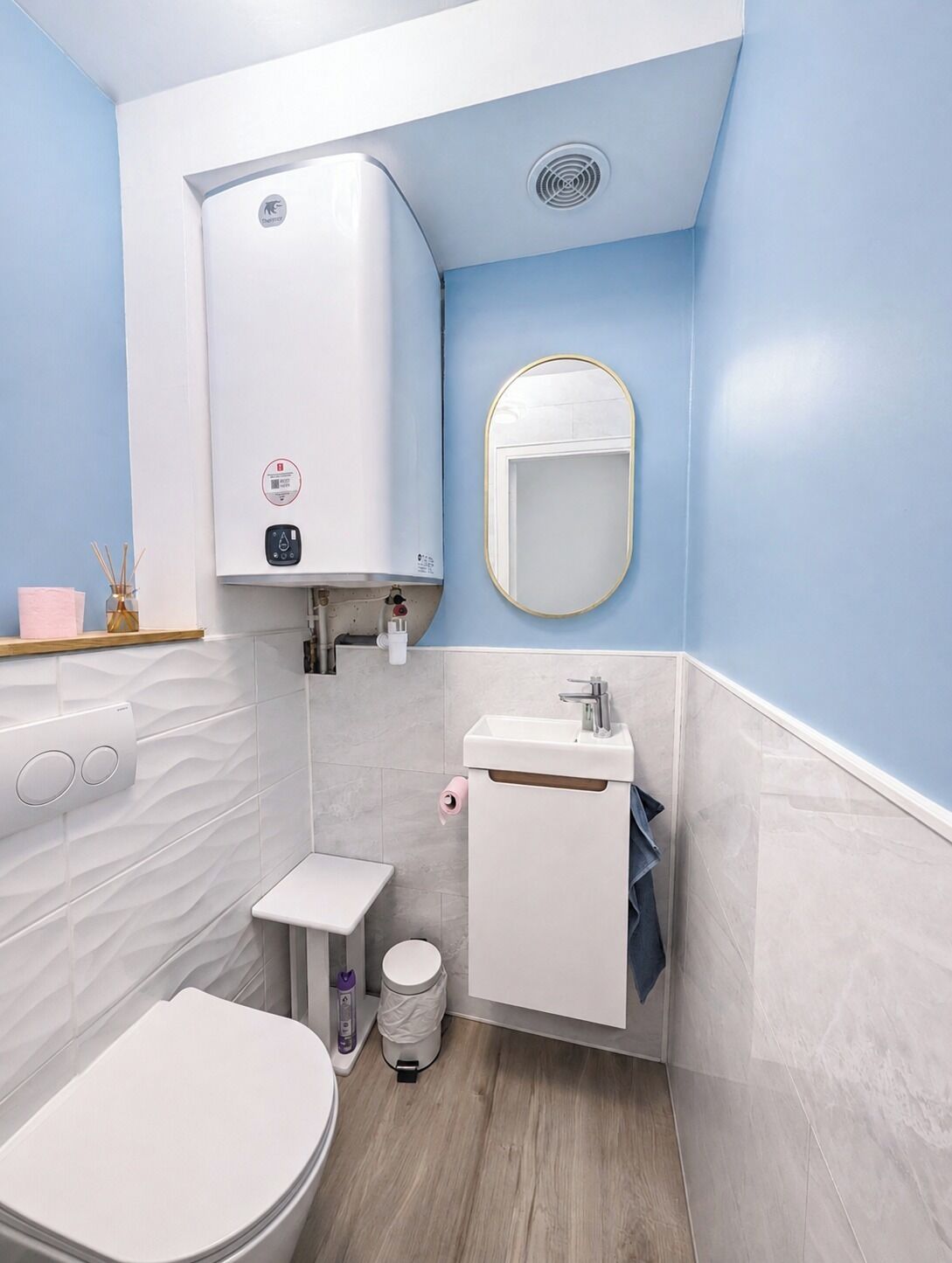 Un bagno compatto con il water, lavandino e un dispenser di asciugamani.