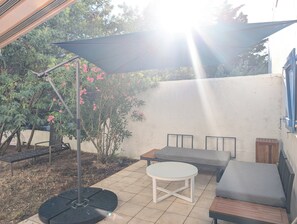 An outdoor patio with a round table, two sofas, and a large umbrella. - N0 Apt, 3-star rated, GF & 200 m² garden, 150 m from the beach – La Guérinière (La Guérinière)