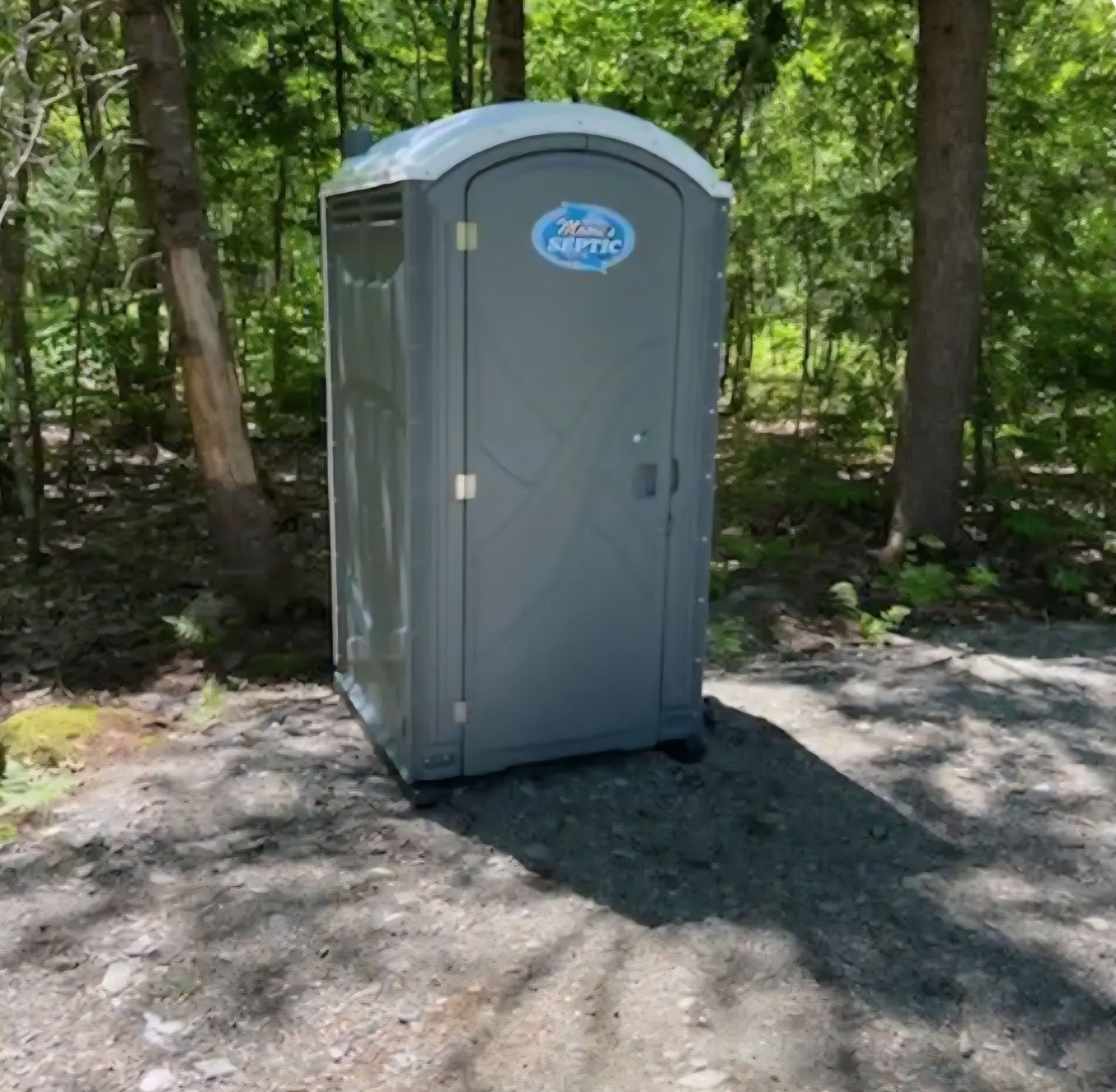 A portable toilet in a wooded area.