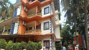 A multi-story residential building with balconies, a gated entrance, and a parked car. - Suite With Balcony Kris Resort (Calangute)