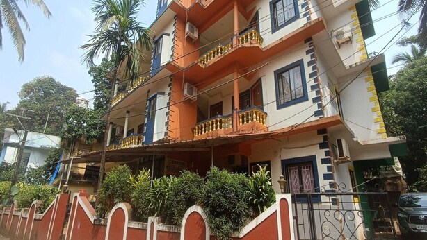 A multi-story residential building with balconies, a gated entrance, and surrounding greenery. - Suite With Balcony Kris Resort (Calangute)