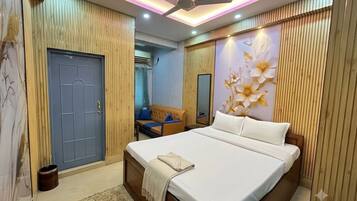 A bedroom with a bed, a ceiling fan, a wooden door, and a wall with a floral design.
