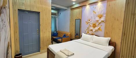 A bedroom with a bed, a ceiling fan, a wooden door, and a wall with a floral design.