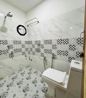 Un baño con ducha, inodoro y espejo.
