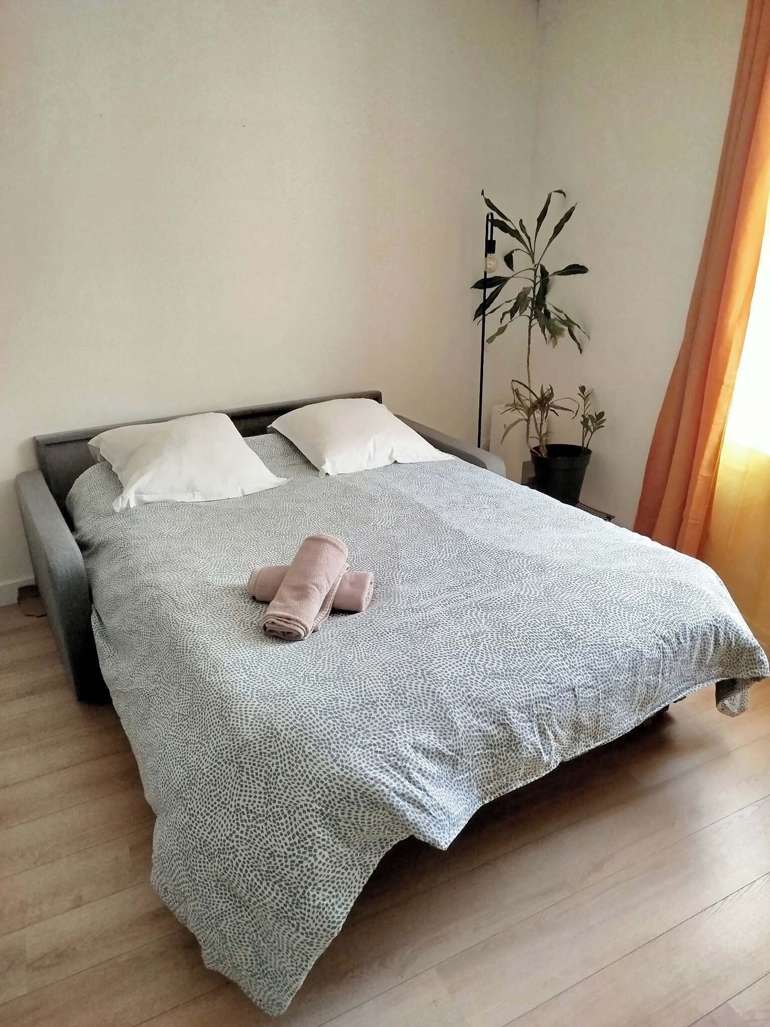 Un lit bien fait, avec une couvre-lit à motifs, des oreillers et des serviettes enroulées.