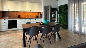 Una cucina moderna con mobili bianchi, un piano di lavoro in legno e un'area pranzo con tavolo e sedie.