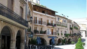 Un edificio con varios balcones, mobiliario exterior y un letrero que dice 'SCHINER'.