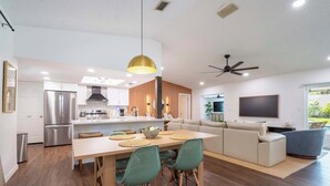 A modern kitchen with a dining area, a sofa, and a TV. - Seminole Family Escape: Pool, Games & BBQ (Seminole)
