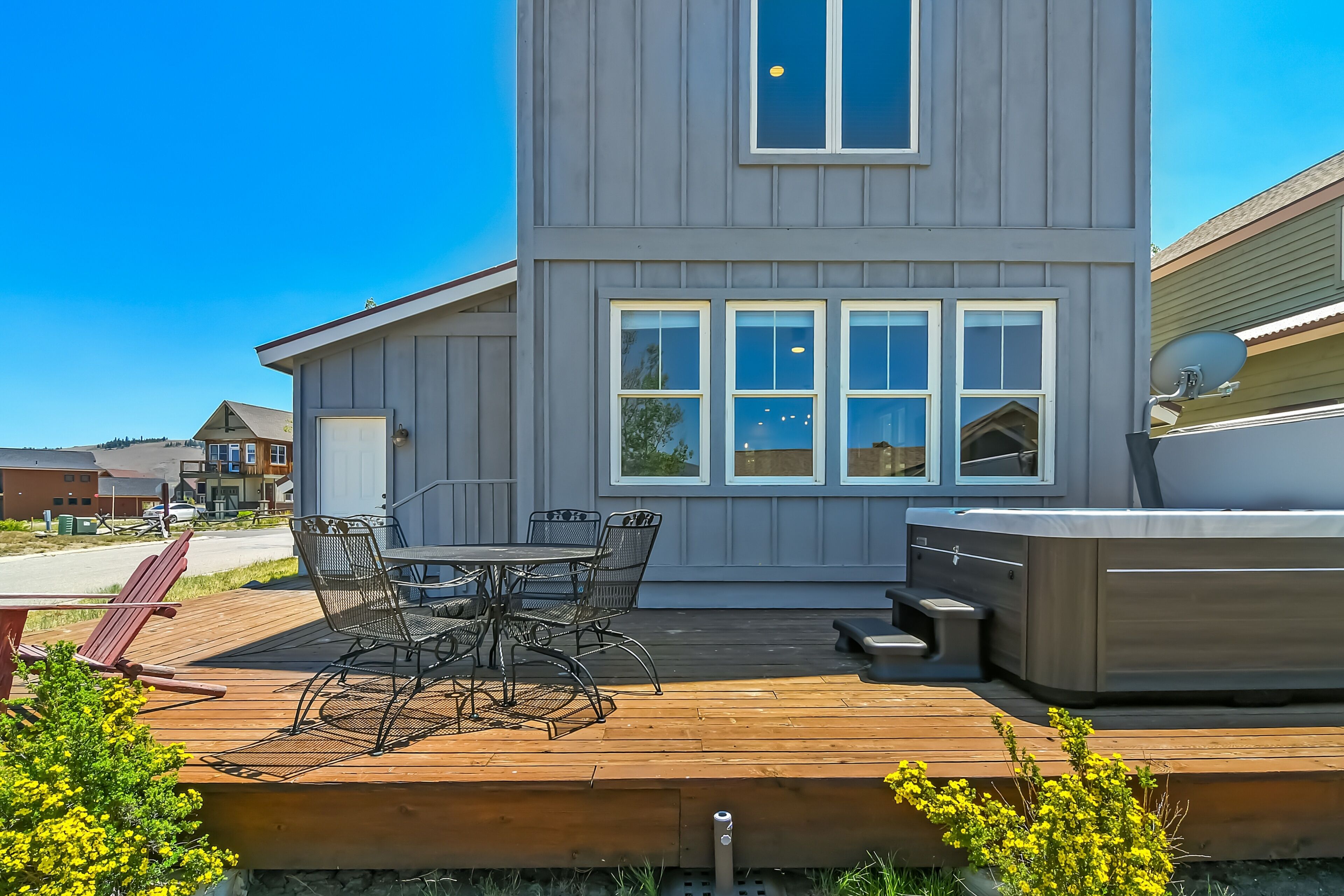 A modern house with a deck, a hot tub, and a patio table with chairs.