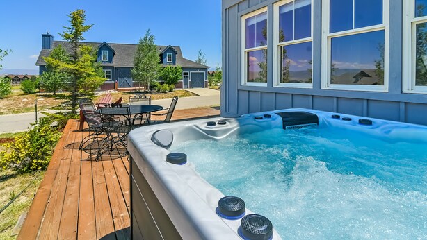 A hot tub on a wooden deck with a view of a house and trees. - Buckhorn Reserve 3 Bedroom Cabin (Granby)