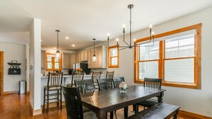 A dining area with a wooden table, chairs, and a chandelier. - Buckhorn Reserve 3 Bedroom Cabin (Granby)
