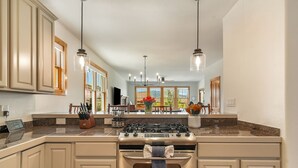 A kitchen with a stove, oven, and hanging pendant lights. - Buckhorn Reserve 3 Bedroom Cabin (Granby)