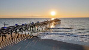 A pier extending into the sea with a sunset in the background. - Buoy Haus: Brand-New 2027 Inlet Front Escape w/Pool, Spa & Dock (Murrells Inlet)