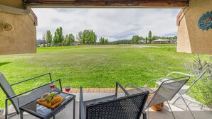 An outdoor patio with a table and chairs, a grassy lawn, and a view of the surrounding area. - Aspen Run Condo Unit 29A | Great Views & Location! (Ruidoso)