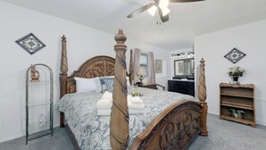 A bedroom with a four-poster bed, a ceiling fan, a dresser, a vanity with a mirror, and a small shelf with decorative items. - Aspen Run Condo Unit 29A | Great Views & Location! (Ruidoso)