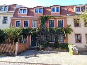 Reihleinfamilienhäuser mit mittlerem Eingang, Holzlattenzaun und gepflasterter Auffahrt.