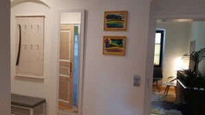 A hallway with a mirror, two framed paintings, a coat rack, and a potted plant. - Vacation Rental T19-Dresden (Dresden)