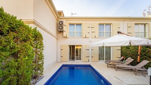A swimming pool with a tiled edge, a covered patio with lounge chairs, and a building with beige walls and shutters. - Villa Medea in Vabriga - Haus für 4 Personen (Vabriga)