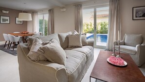 A living room with a sofa, a coffee table, a dining table with chairs, and a view of a pool. - Villa Medea in Vabriga - Haus für 4 Personen (Vabriga)