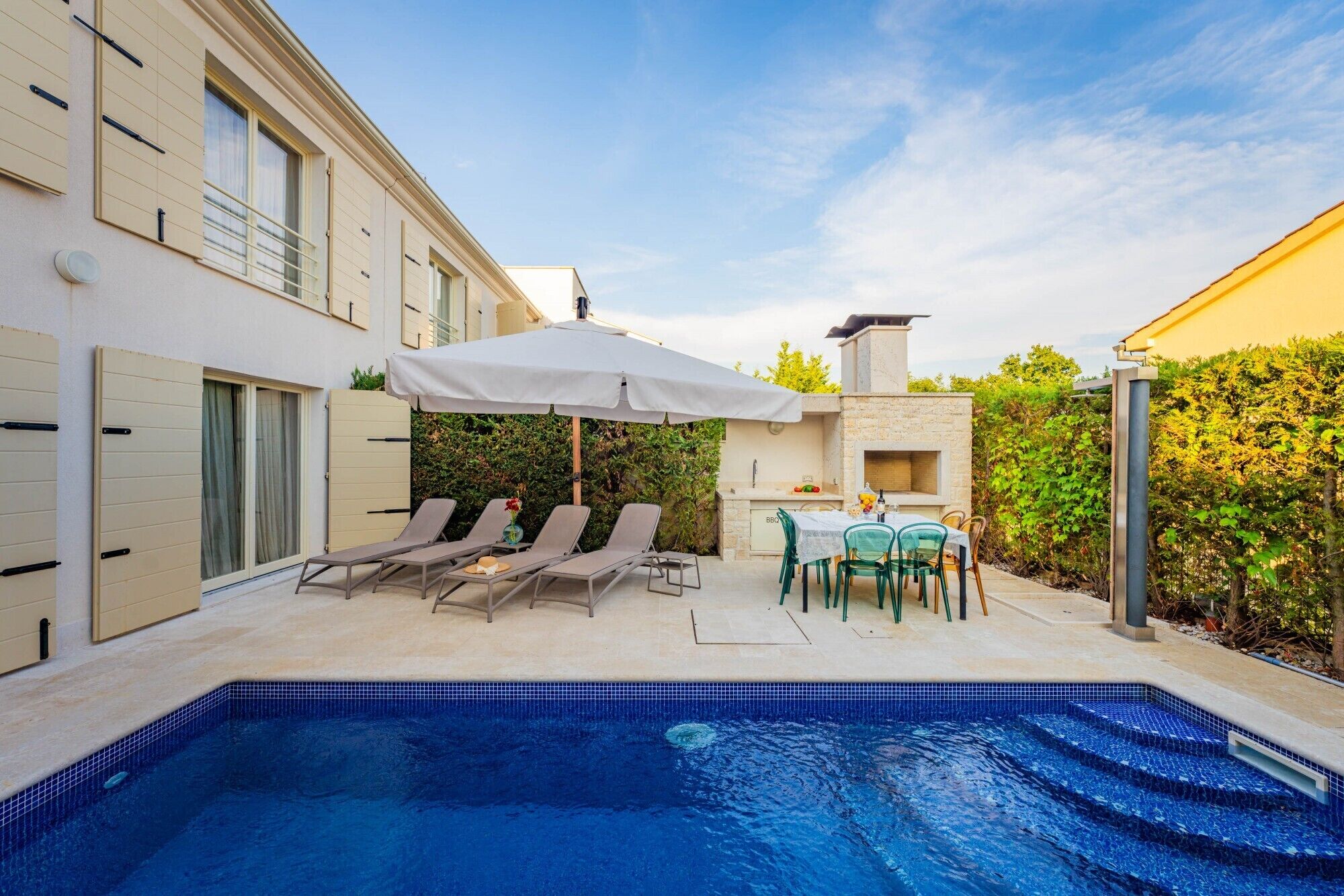 A swimming pool with lounge chairs and a barbecue area.