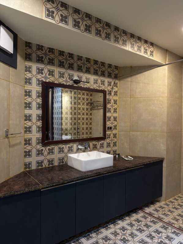 A bathroom with a white sink, dark cabinets, and patterned tiles on the walls and floor.