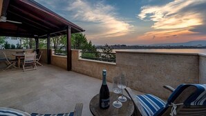 A terrace with a table, chairs, a bottle of wine, and glasses.