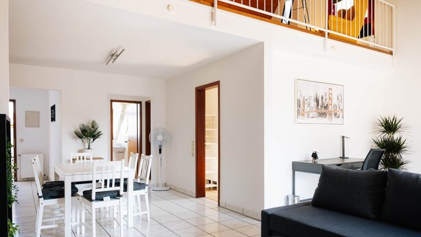 Un salon moderne comprenant un coin repas, un canapé, une petite table et un escalier.
