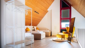 Une chambre moderne avec un lit en mezzanine, un canapé, un fauteuil et un radiateur.