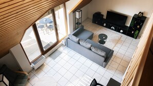 Un salon moderne avec un canapé gris, un téléviseur et une petite table basse.