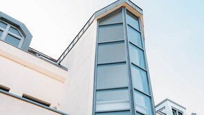 Ein modernes Gebäude mit markantem Eckbereich, großen Fenstern und einer sichtbaren Satellitenschüssel.
