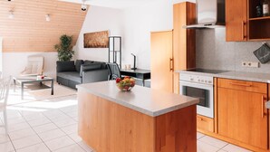 Eine moderne Küche mit Holzschränken, einer Mittelinsel und einem Essbereich mit einer Couch und einem Tisch.