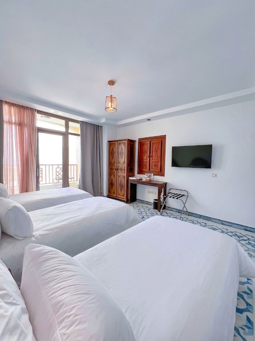 Habitación de hotel con dos camas, televisión, escritorio y armario.