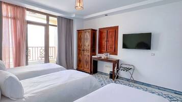 Habitación de hotel con dos camas, televisión, escritorio y armario.