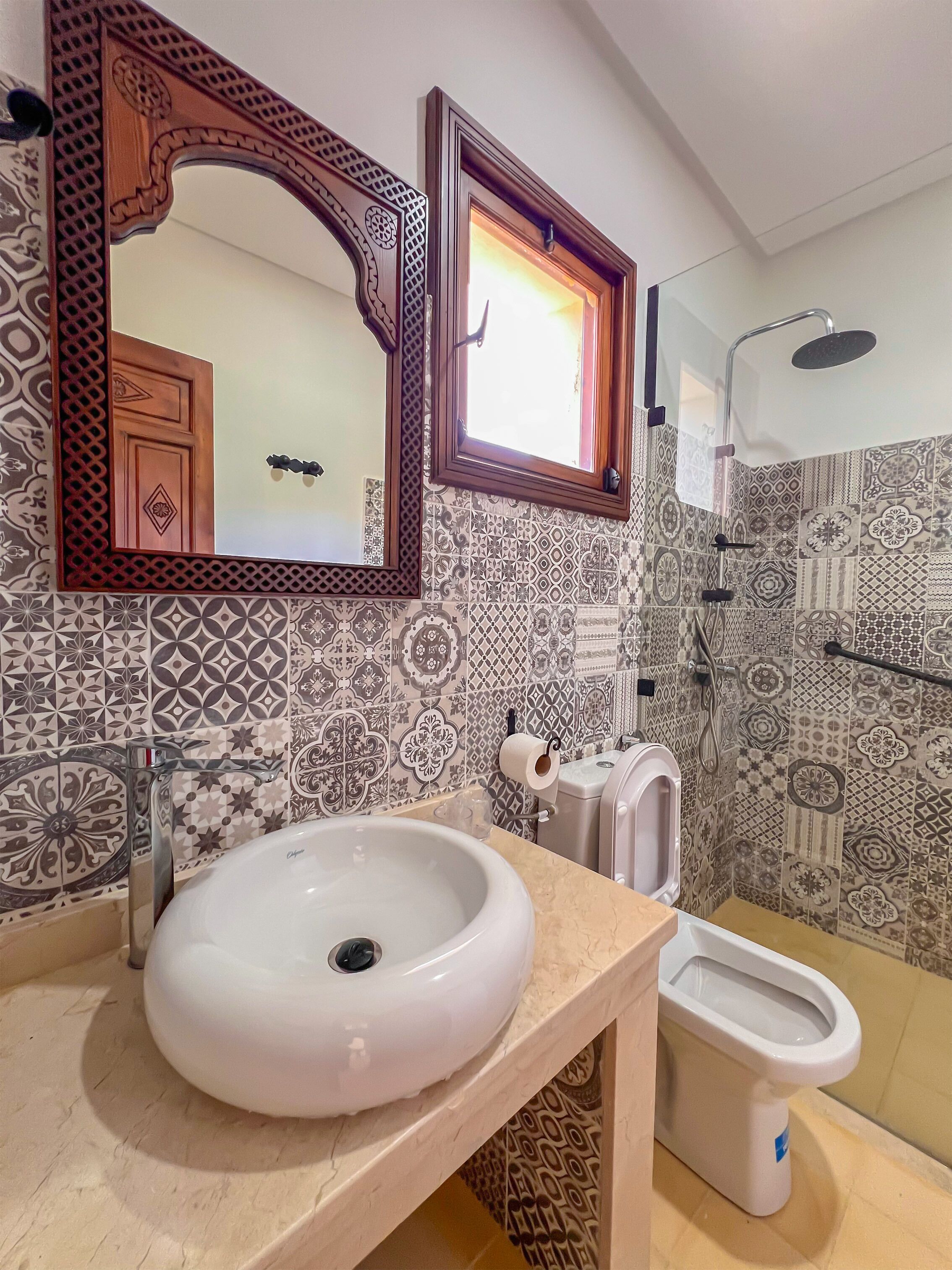 Une salle de bain équipée d’un lavabo, de toilettes, d’une douche et d’un miroir avec un cadre décoratif.
