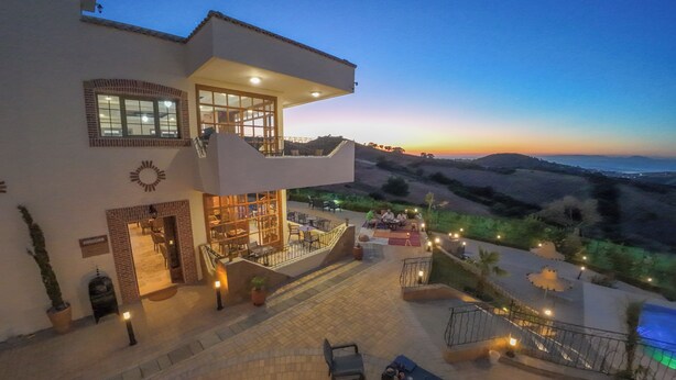 A modern building with a patio area, outdoor seating, and a view of the landscape.
