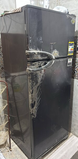 A black refrigerator with a damaged door and a sticker on the side. - Pharaonic 2BR Apt Near Giza Pyramids GEM AC WiFi Balcony (Giza)