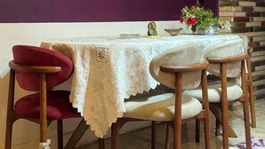 Ein Essbereich mit einem Tisch für vier Personen, einer violetten Wand und einer Wandverkleidung aus Backsteinen.