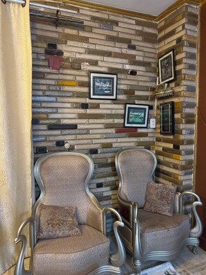 A room with a brick-patterned wall, two upholstered chairs with metal frames, and framed pictures. - Pharaonic 2BR Apt Near Giza Pyramids GEM AC WiFi Balcony (Giza)